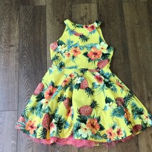 A tropical yellow dress with flowers and pineapples on it.